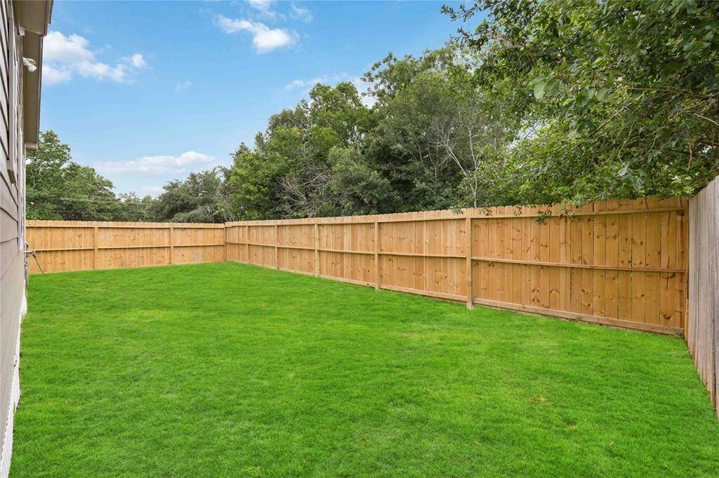 Spacious backyard with lush green grass, enclosed by a wooden privacy fence, ideal for outdoor activities and relaxation.