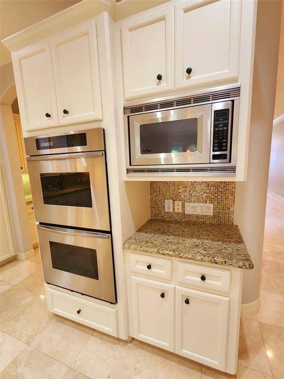Kitchen view of double ovens and microwave located to the left of the cooktop.