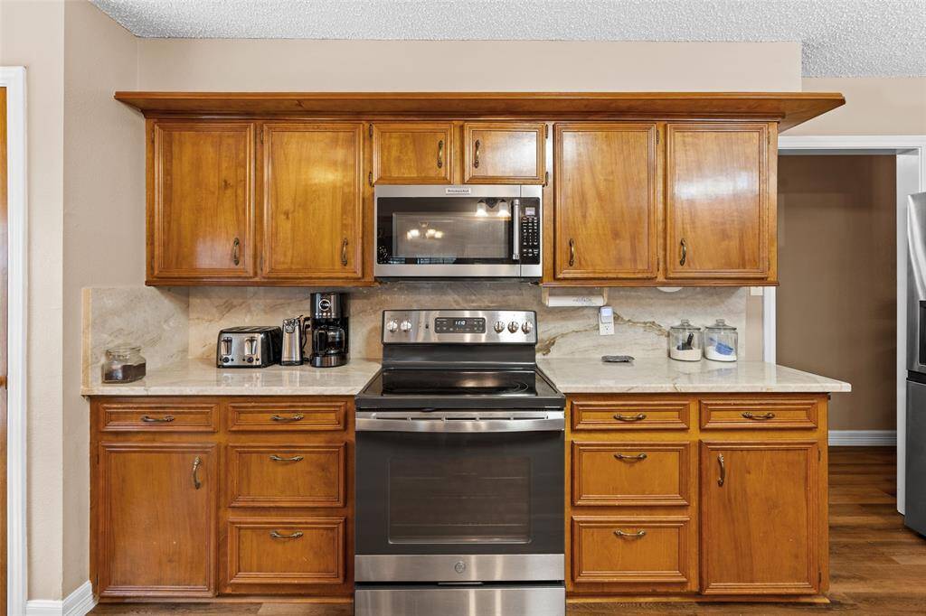 This kitchen features ample counter space with a classic backsplash. It's equipped with modern appliances and offers a cozy, functional cooking area.