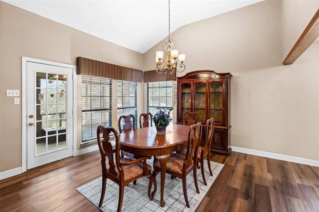 The spacious dining room features vaulted ceiling and is brightened by large windows and a glass door leading outside to the screened in balcony.