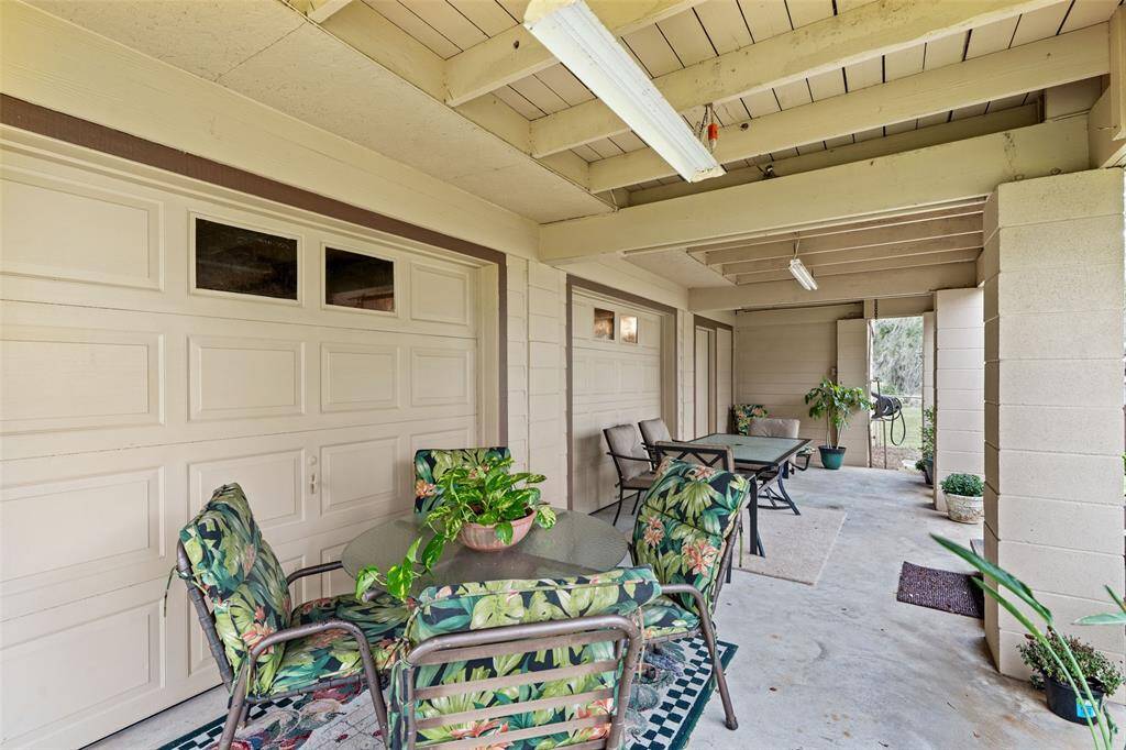 Covered patio area with ample seating, offering a cozy outdoor space next to the garage.