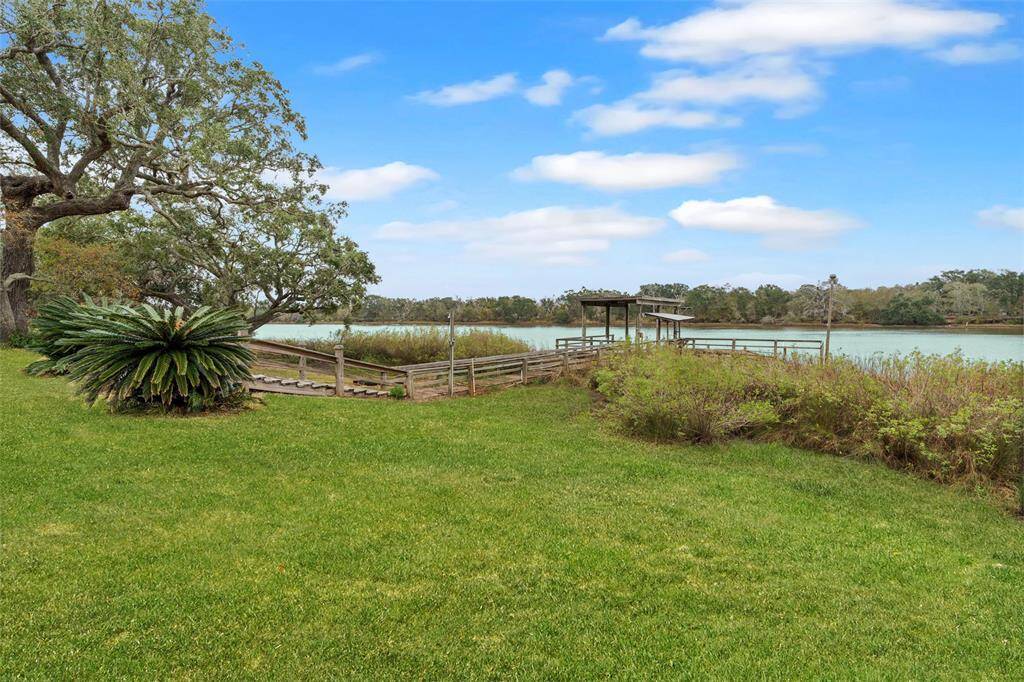 Peaceful waterfront living with a wooden deck, framed by mature trees and vibrant foliage, perfect for nature lovers.