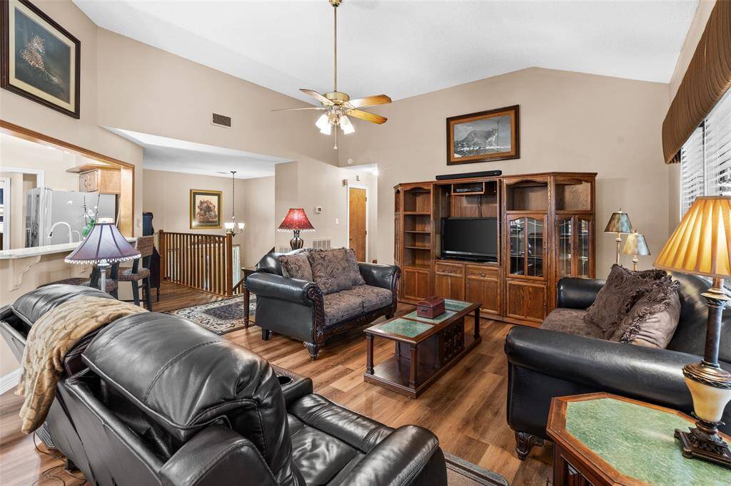 The inviting living room features high ceilings, warm neutral tones, and ample natural light. The open layout flows into the dining area and kitchen, enhancing the spacious feel.