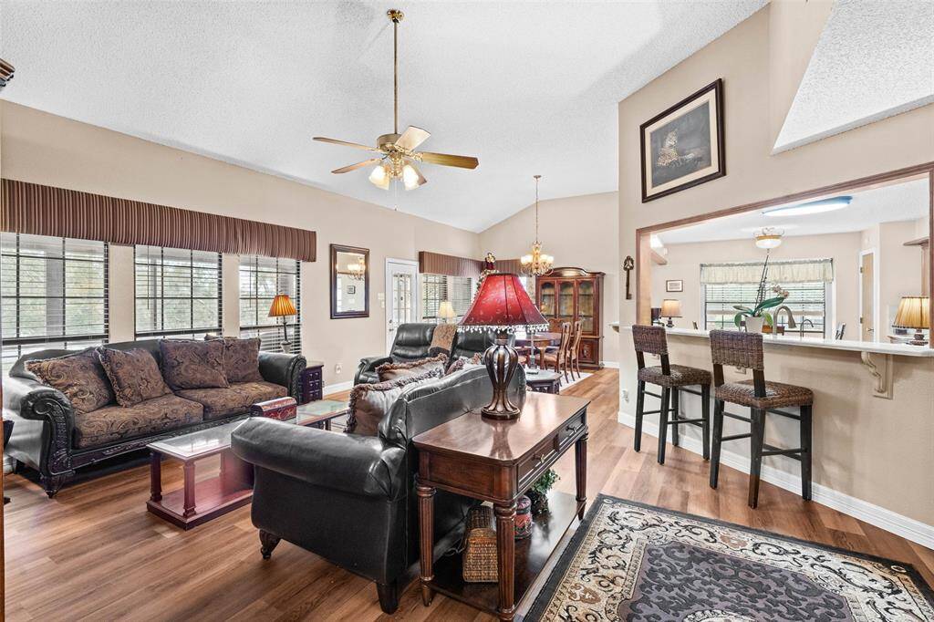 Open-concept living area features elegant engineered wood flooring and plenty of windows. The breakfast bar connects to the kitchen, enhancing the flow for entertaining.