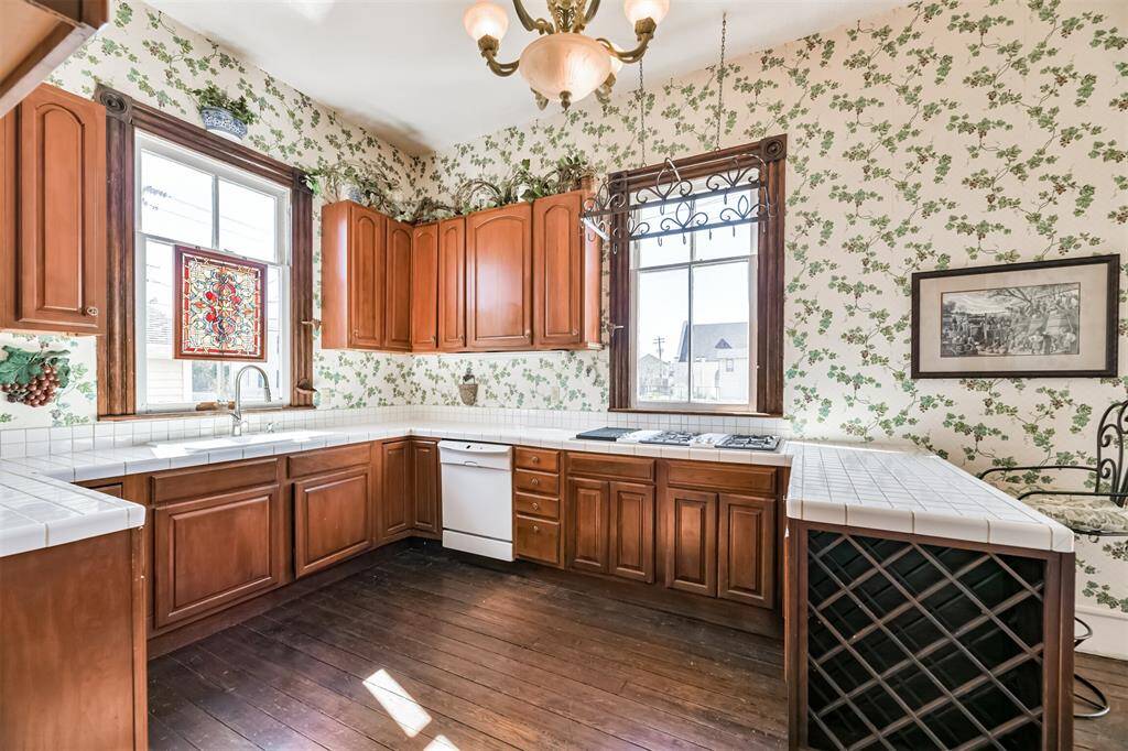 Tucked near the rear of the home, with direct access to the dining room and back door, this kitchen features an abundance of cabinetry topped by classic white tile countertops. You'll even find a wine storage rack built-in!