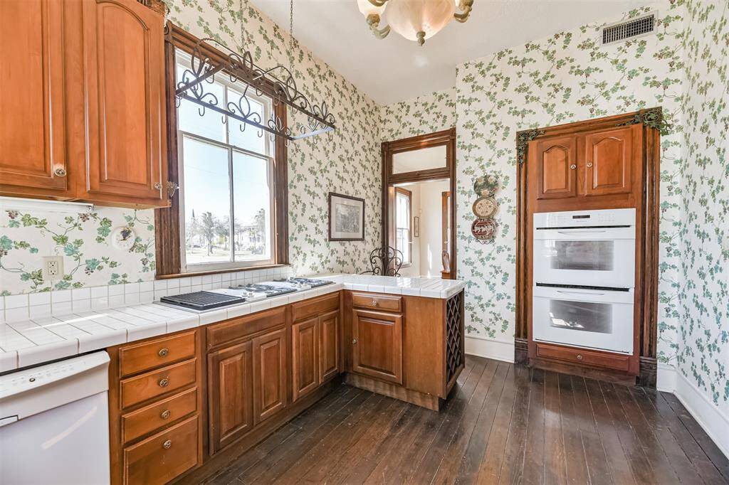 Modern conveniences make cooking far more simple than it was when this home was constructed! In today's kitchen, you'll find a 4 burner gas cooktop with downdraft and indoor grill, double ovens, a dishwasher, and a cast iron sink with a gooseneck faucet.