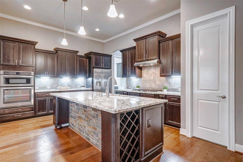 The kitchen features a large island, under cabinet lighting, stainless steel appliance package, wine rack, spice rack, and rollout shelving.