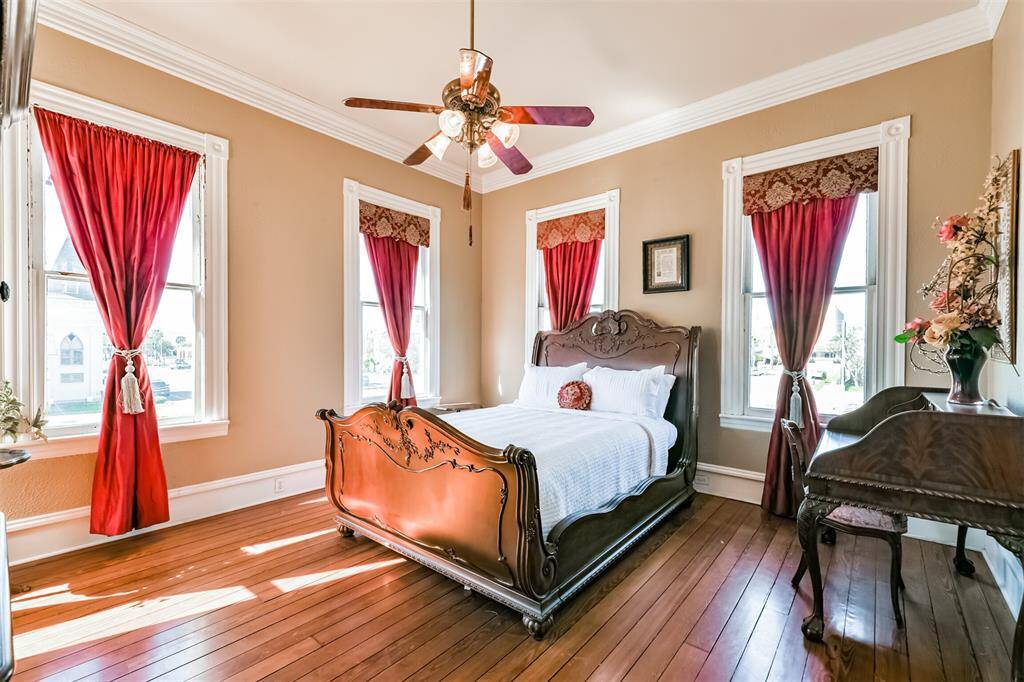 Just off of the second-floor landing, you'll enter this charming bedroom that boasts long leaf pine wood floors, neutral paint, and crisp white moldings that frame the numerous windows that encircle the room.