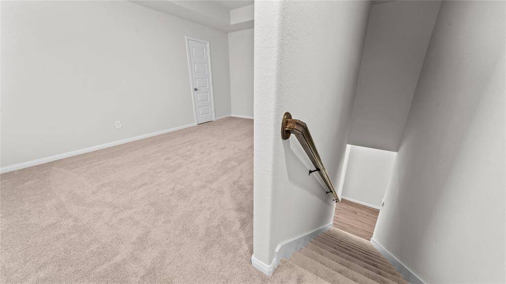 Spacious second floor with plush carpeting, featuring a modern design and easy access via a sleek staircase.
