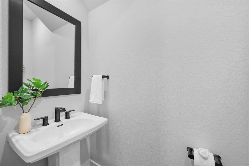 The downstairs powder bathroom has a modern pedestal sink & clean finishes.
