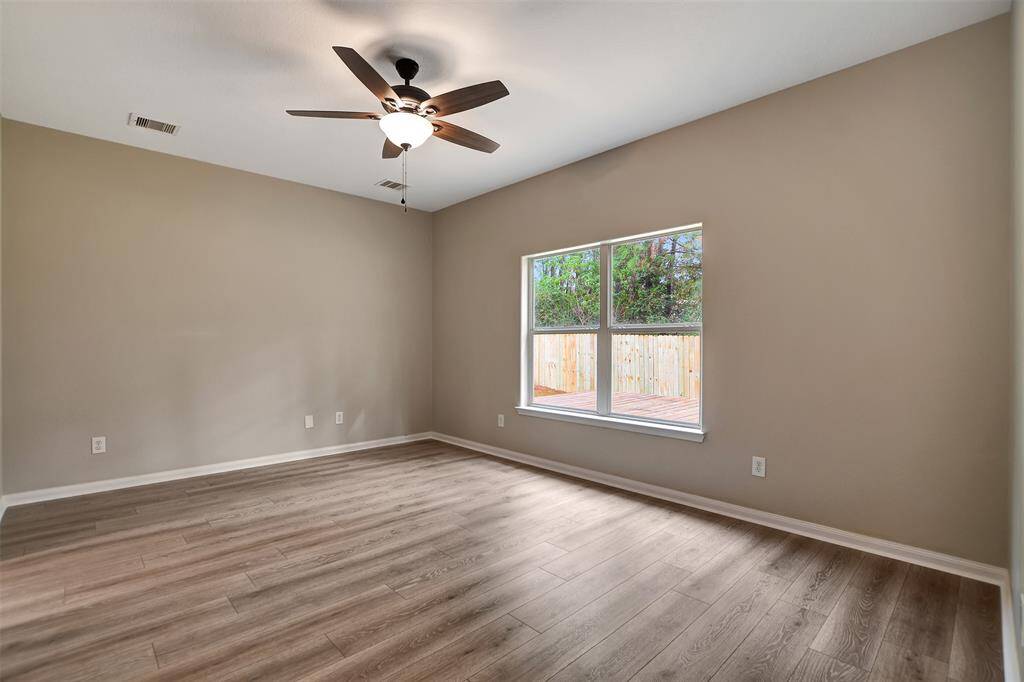 Primary bedroom is down with new flooring, fresh paint and new ceiling fan