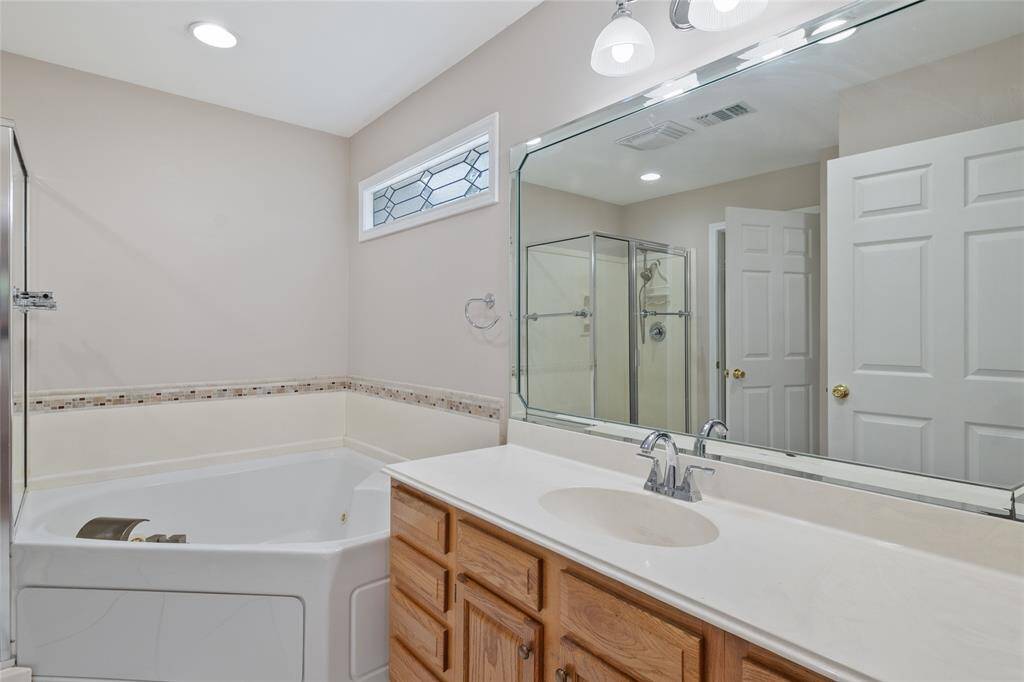The primary bath features more custom built cabinetry and large vanity with Jacuzzi Corner tub.