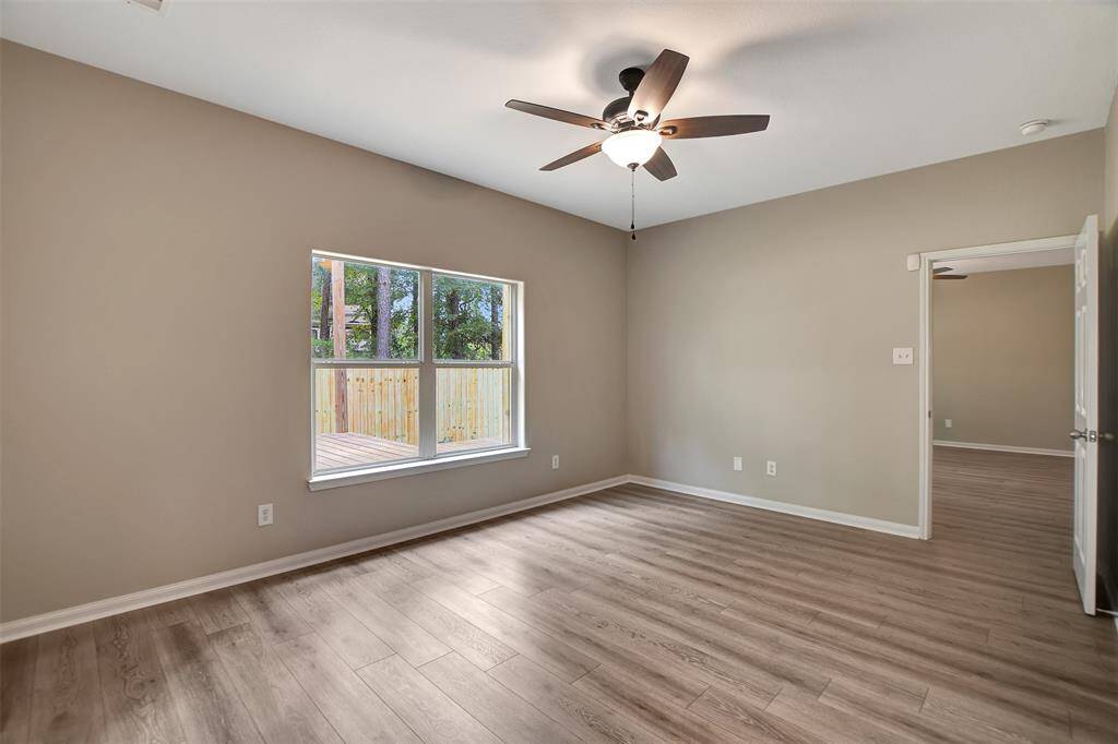 Primary bedroom is off of the den with view to the wooded yard and deck