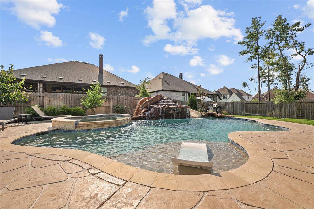 Hand carved patio decking with stone tile embellishments surround the Gunite built HEATED pool with a stonescape mini pebble finish. The pool features a big water fall, small weeping wall, sun tanning ledge with fountain. It also has app controlled lights, water features, and maintenance that can be adjusted wherever you are. So in the winter you can turn on the heated pool so it's warm by the time you get home!