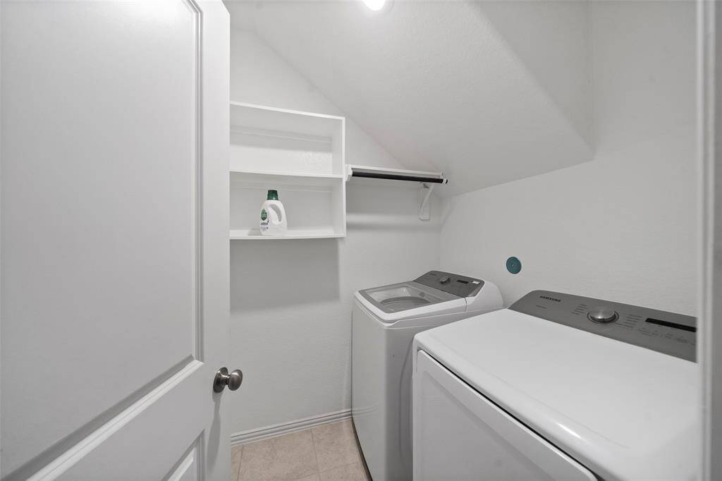 A well-appointed laundry room featuring hanging rod and shelving for storage!