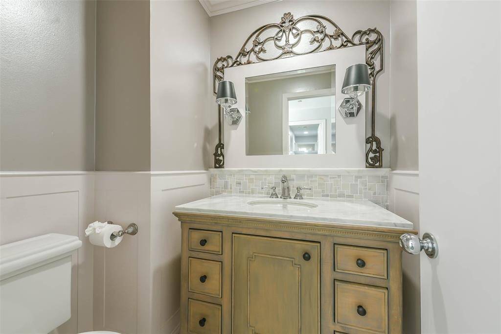 Updated powder room with board and batten wall accent, framed mirror and granite top cabinet.