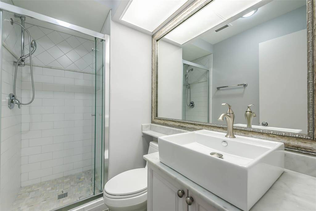 Stylish secondary bathroom with standup shower, vessel sink and custom framed mirror.