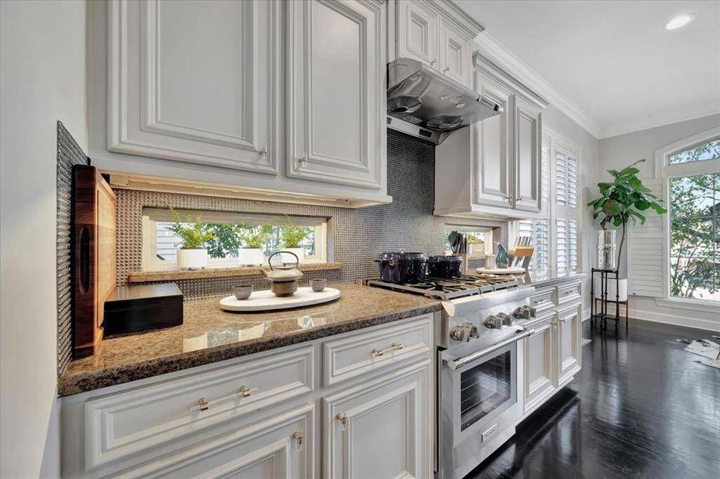A charming transom window between the lower and upper cabinets allows natural light to flood the kitchen, creating a bright and airy atmosphere.