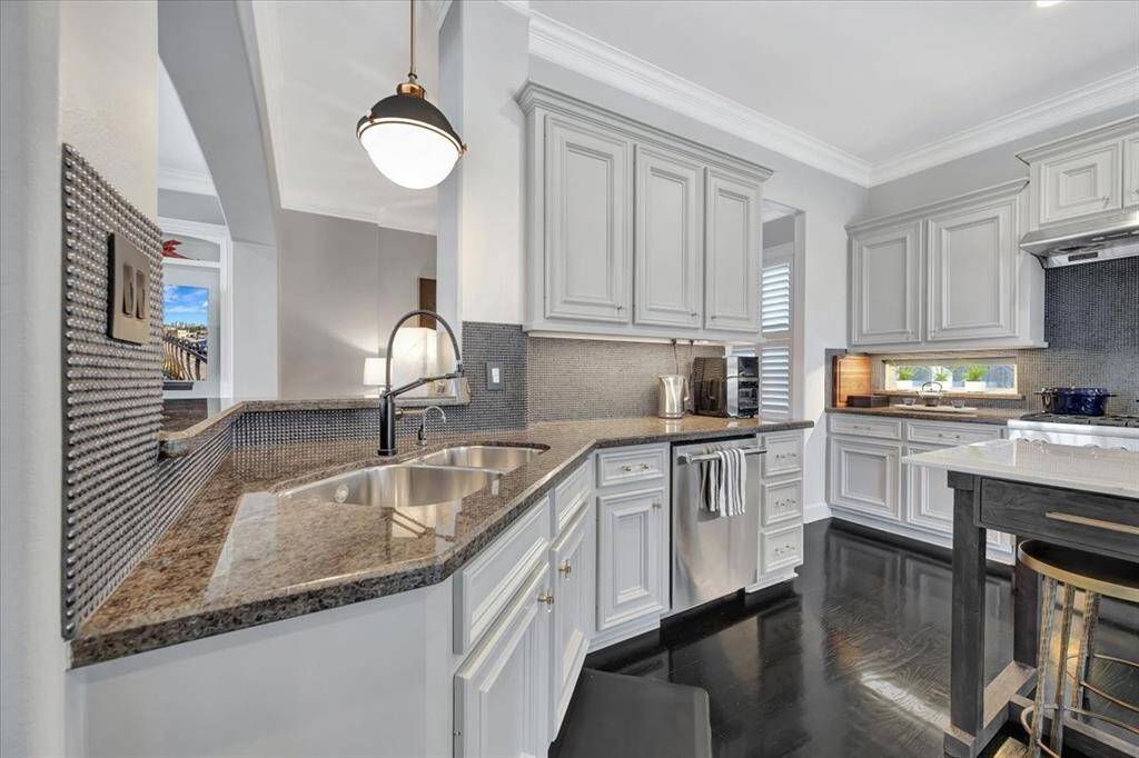 This view of the kitchen showcases a stylish glass pearl tile backsplash, a high-end Thermador dishwasher, and a large open archway that seamlessly connects the kitchen to the family room, creating a perfect flow for entertaining