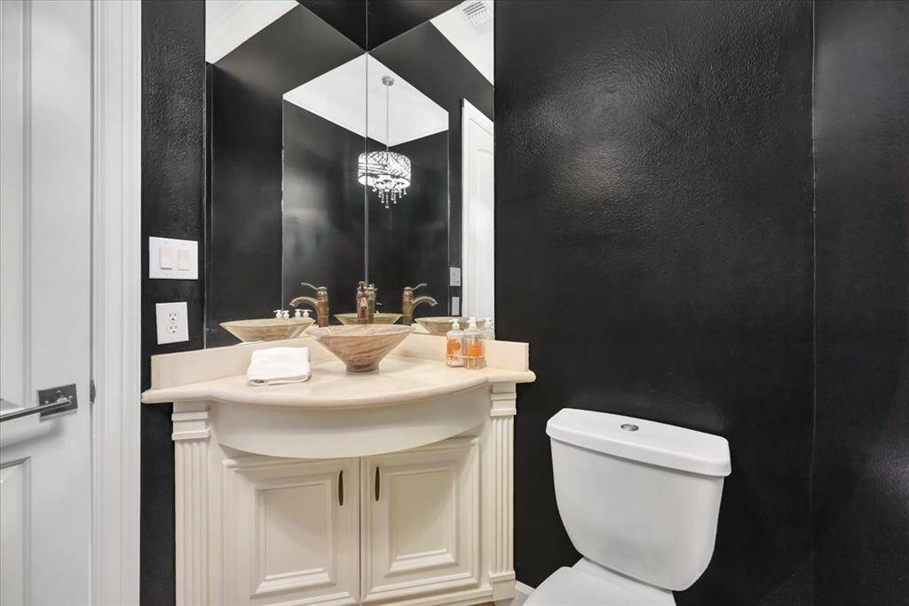 This sleek powder bath features bold black walls, complemented by a chandelier that adds an elegant touch to the space.