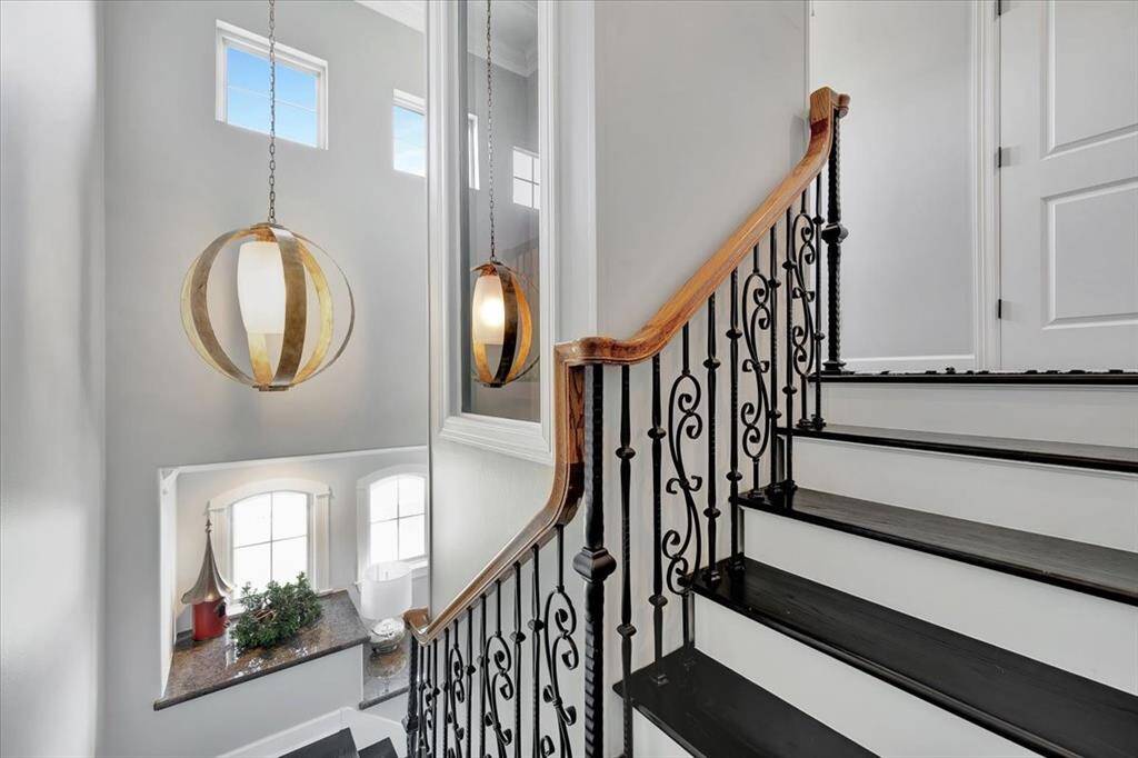 The elegant wrought iron stair railings complement the home's sophisticated style, while granite countertops atop built-in storage just off the stairs offer both functionality and beauty.