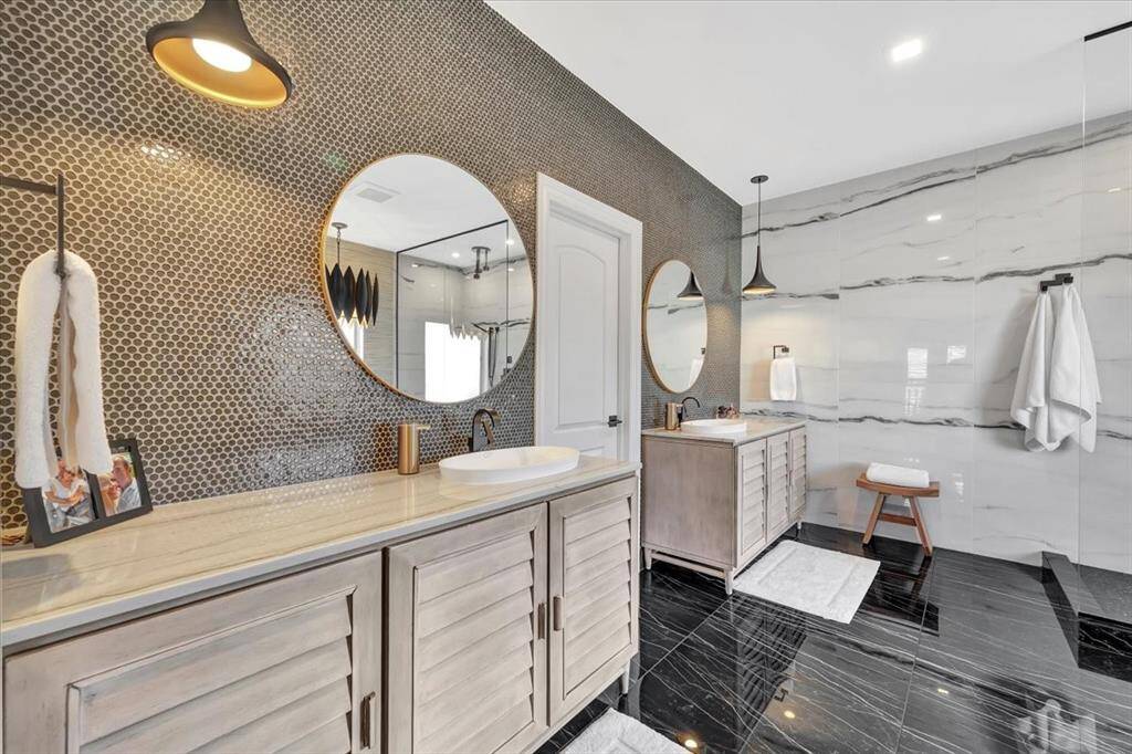 The ensuite with it's modern and clean feel offers his and hers vanity and a wall of elegantly lined penny tile and feature pendant lighting.