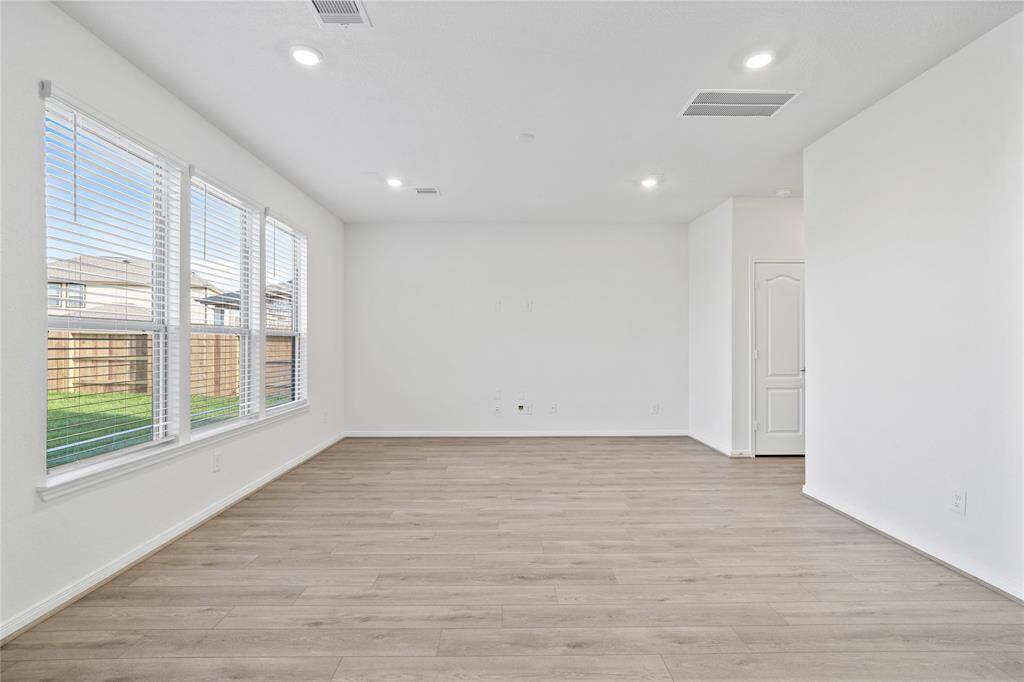 This light and bright Great Room features vinyl plank flooring, large windows with blinds, high ceilings, recessed lighting with wonderful access to your gorgeous kitchen.