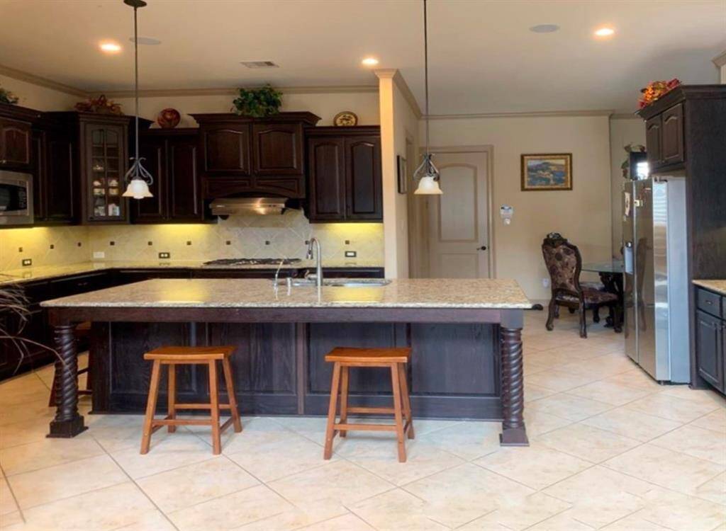 The gourmet kitchen includes a 5-burner gas stove, granite countertops, tile backsplash, double convection ovens, a large eat-in bar, and a reverse osmosis system.