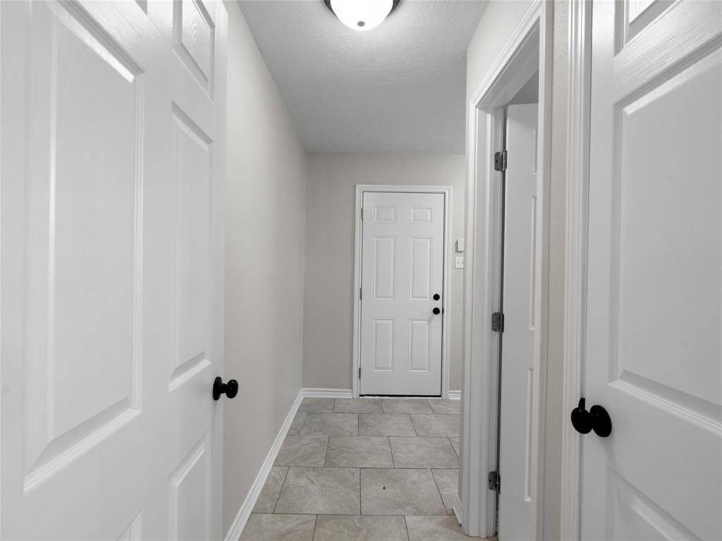 The hallway from the kitchen leads to the half bath, in-house utilities & garage