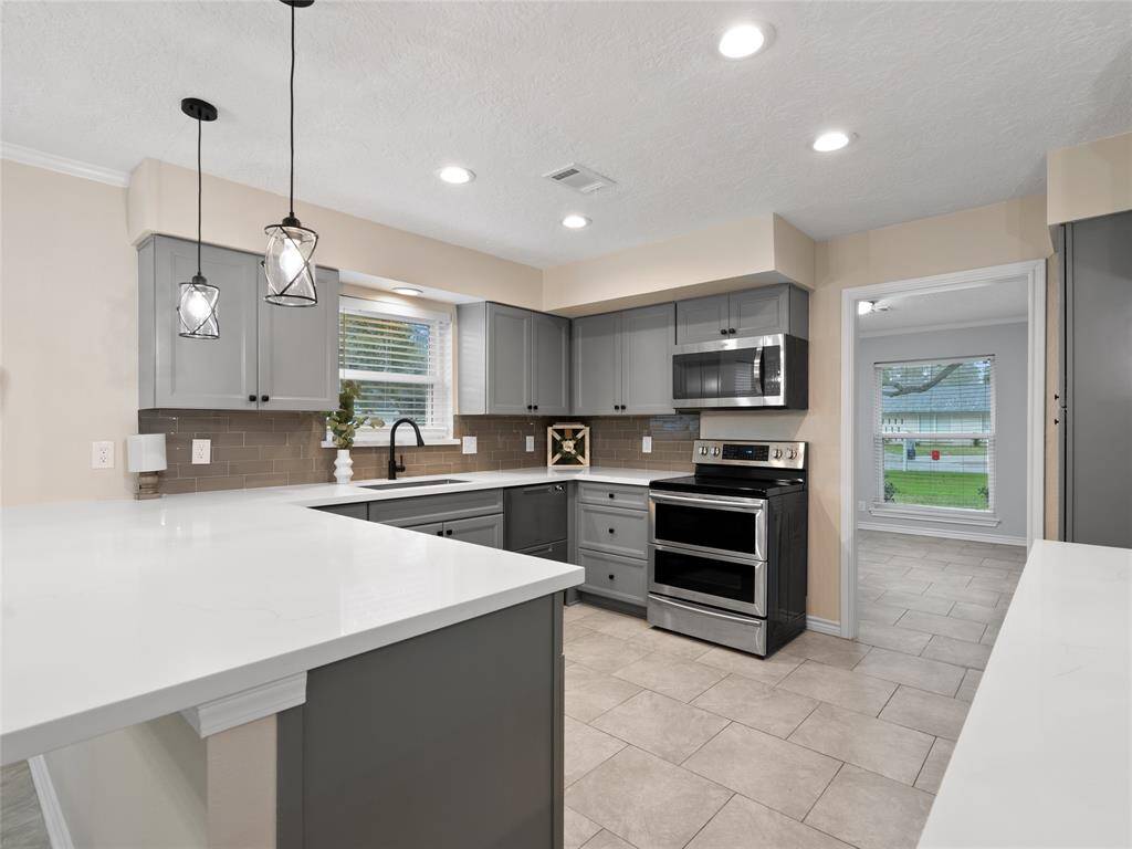 The updated kitchen with freshly painted cabinets, new quartz countertops, new backsplash, lighting & breakfast bar
