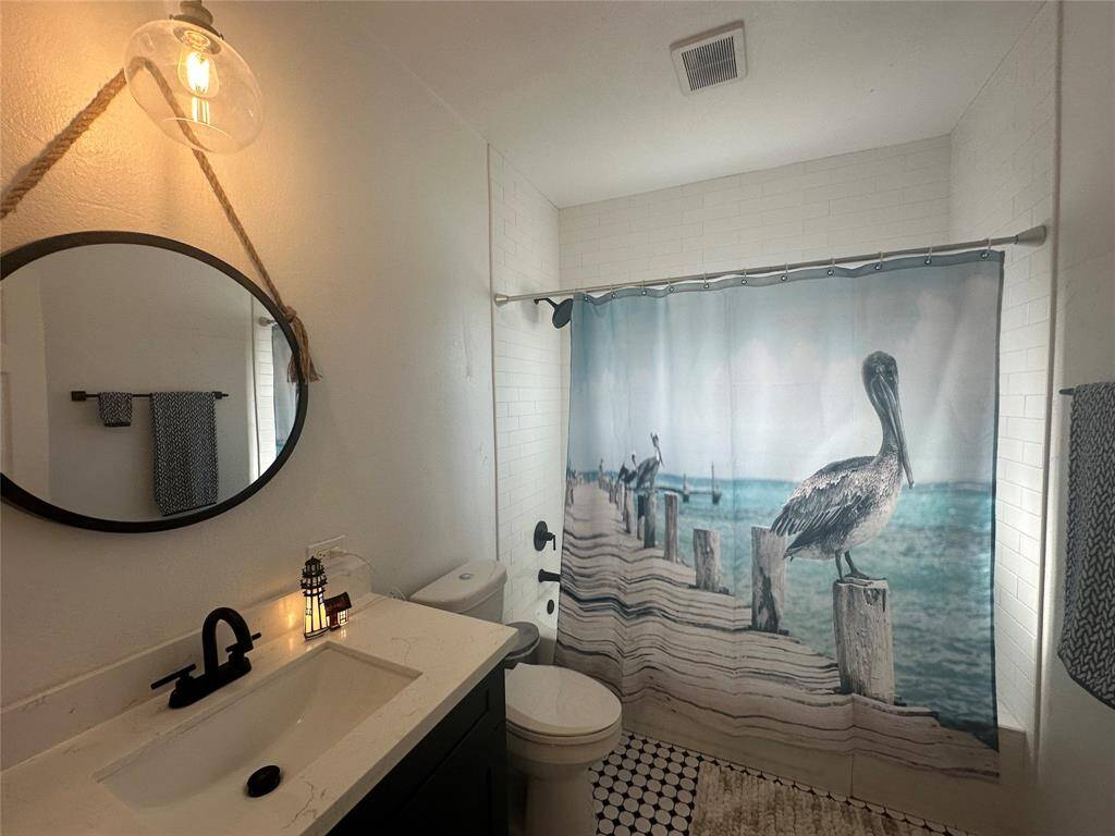 The bathroom is definitely move-in ready! Featuring navy blue stained cabinets with light countertops, high ceilings, custom paint, gorgeous flooring and dark modern finishes.