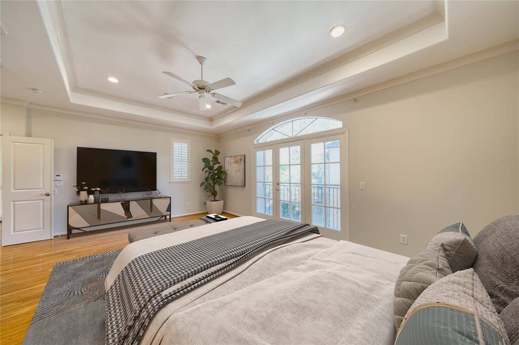 Gorgeous primary bedroom with elegant tray ceiling, hardwood floors, and abundant natural light.