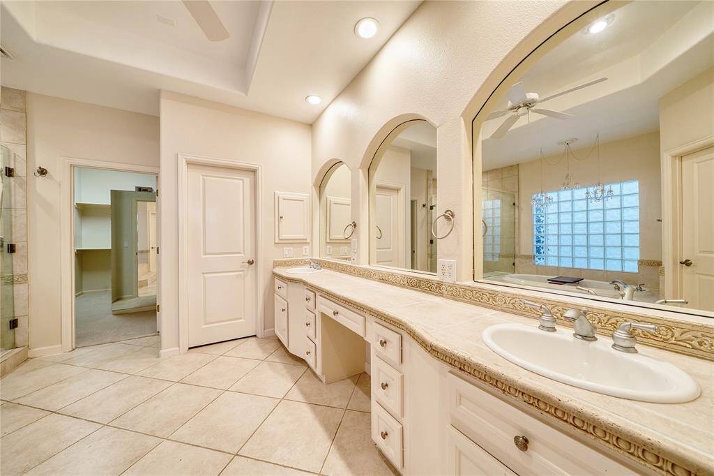 Luxurious primary bathroom with double vanities and direct walk-in closet access.
