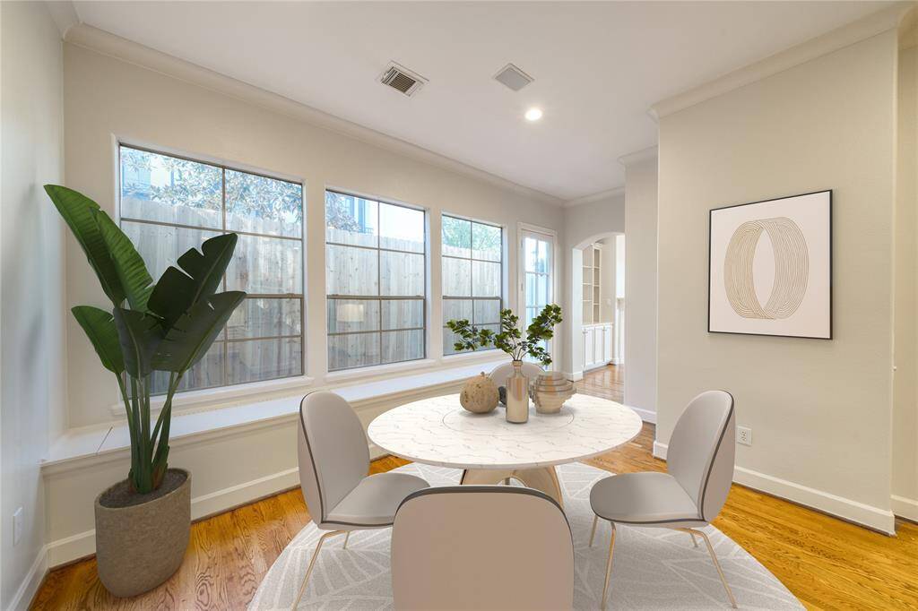 Enjoy the view of a cozy breakfast nook, featuring a wall of windows that flood the space with natural light. The space includes a door leading to the backyard with built-in bench seating and storage, creating a bright and functional retreat.