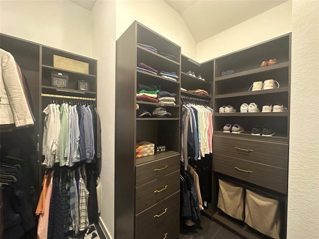 This additional view of your spacious walk-in closet with custom shelving and built-ins