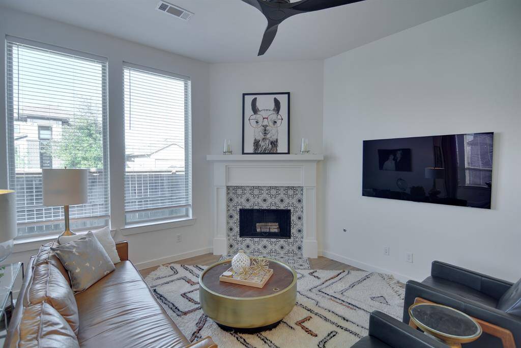 The expansive living room offers a modern, open-concept design filled with natural light from large windows. The soaring ceilings enhance the spacious feel, while the neutral tones and fireplace invite relaxation. Ideal for both everyday comfort and stylish gatherings, this space exudes luxury and warmth.