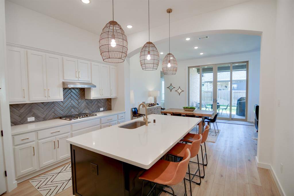 This stunning kitchen displays such a beautiful contrast with the two toned cabinets, neutral paint, Quartz countertops, light modern backsplash, stainless steel appliances, oversized kitchen island with extra storage, breakfast bar, recessed lighting, high ceilings and farmhouse sink and wood look luxury vinyl plank flooring.