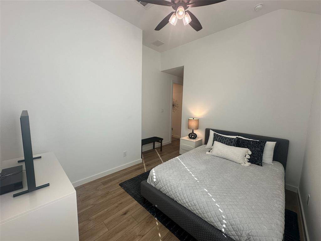 Secondary bedroom great for use as an in-law suite or guest suite features it's very own private bathroom along with high ceilings, modern ceiling fan with lighting, neutral paint, wood look luxury vinyl plank flooring and space for seating area.
