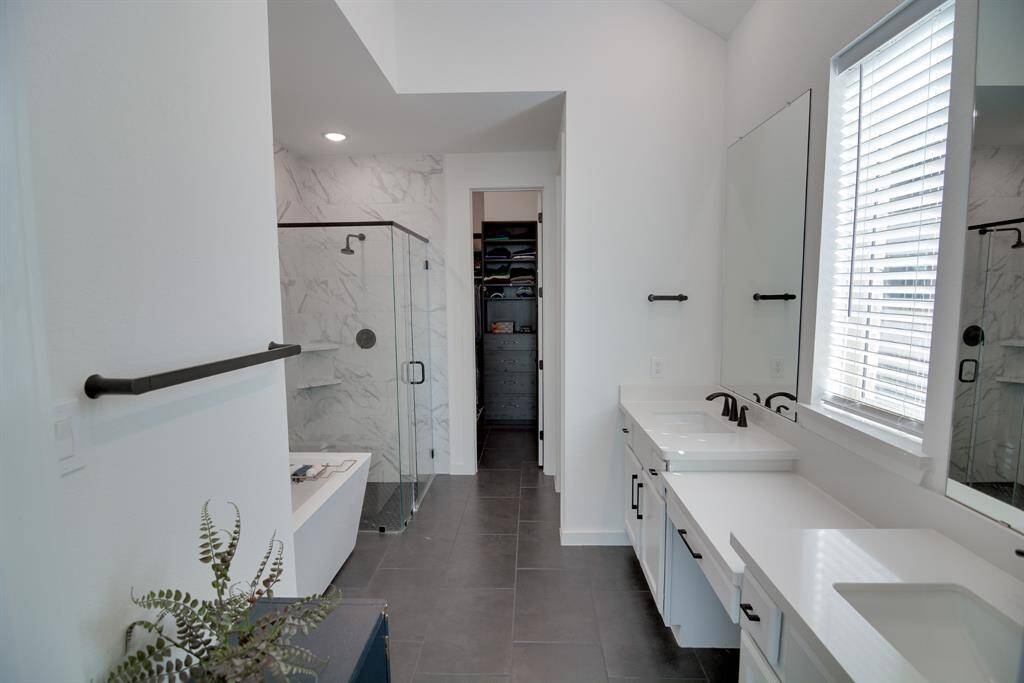 This primary bathroom is definitely move-in ready! Featuring a spa like oversized walk-in shower with tile surround, separate garden spa like tub for soaking after a long day with custom tile detailing, light stained cabinets with light countertops, spacious walk-in closet with custom shelving and built-ins, high ceilings, custom paint, sleek and modern finishes.