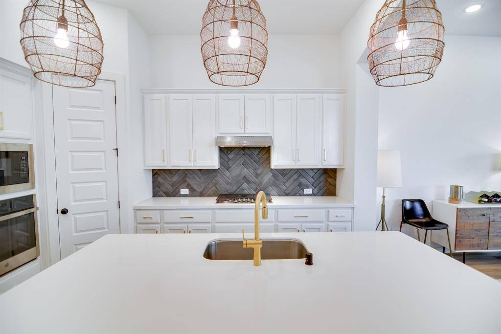 Elegant and modern lighting greets you as you enter this beautifully designed kitchen. The stunning chandelier pendant lighting creates a captivating focal point, cascading down from the ceiling and illuminating the open kitchen. The sleek Quartz countertop island adds a touch of contemporary style, complementing the airy, light-filled space.