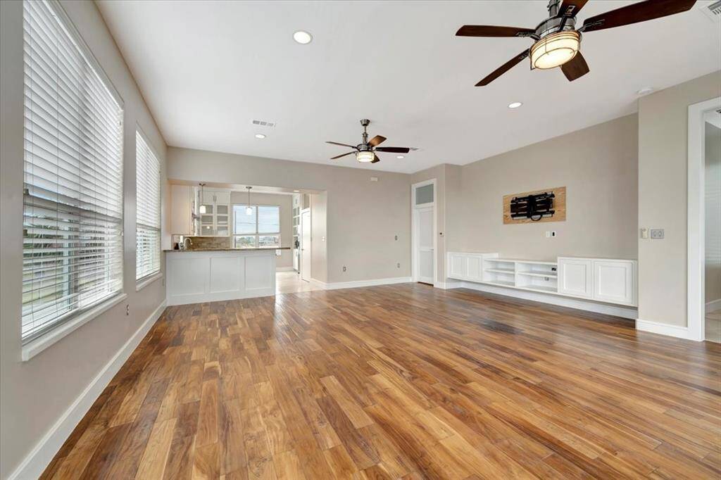 The living and dining combo features rich hardwood floors, enhanced by the warm glow of natural light filtering through faux two-inch blinds, creating a cozy and inviting atmosphere.