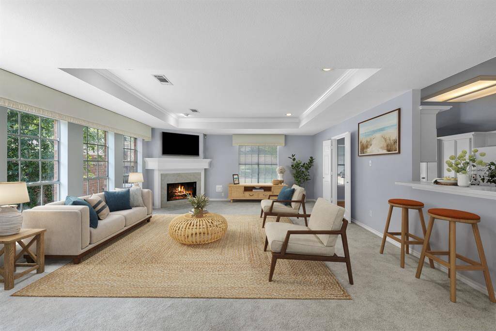 The virtually staged family room is flanked by a gas log fireplace and a wall of windows. The windows flood the home with natural light and spotlights its architectural beauties.