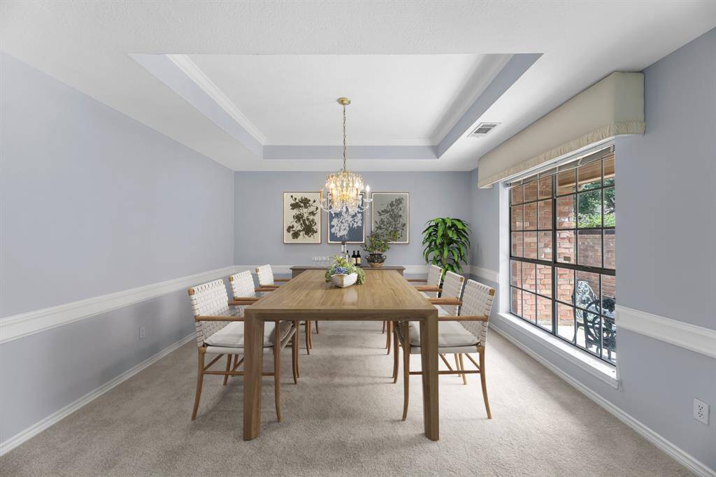 The virtually staged dining room has a stunning crystal chandelier and its tray ceiling adds a touch of sophistication.
