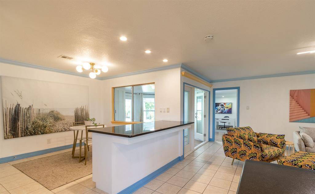 Breakfast area has its own breakfast bar. Sunroom in the background with the windows and doors. Fourth bedroom/home office in the far background. Living room to the right.
