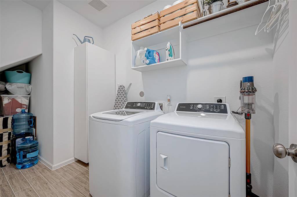 This photo showcases a well-organized laundry room. It features shelving for storage, a cabinet, and space for additional items, providing a functional area for laundry needs. (Washer/Dryer excluded from the sale)
