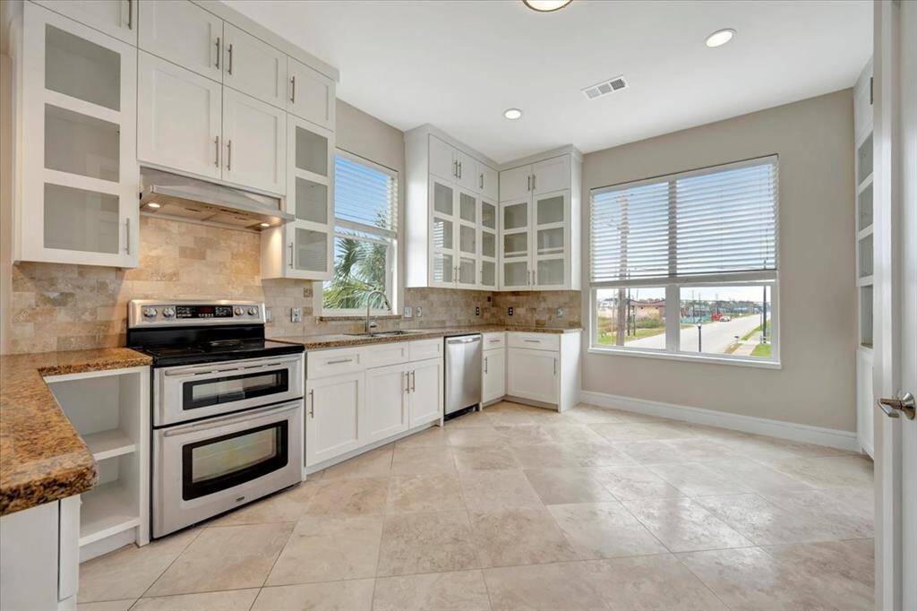 A stylish kitchen showcasing glass-front cabinets, sleek granite countertops, and elegant travertine floors for a timeless and sophisticated look.