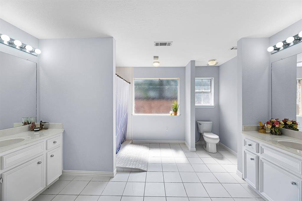 Thee primary bathroom has dual vanities, a roll-in shower, and an abundance of natural light, while still providing privacy.