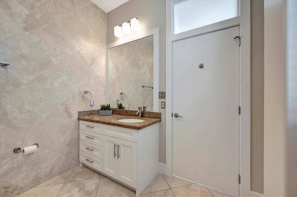 A luxurious bathroom featuring travertine tiles on both the floors and walls, beautifully surrounding a sleek tub and shower combo for a cohesive and spa-like design.