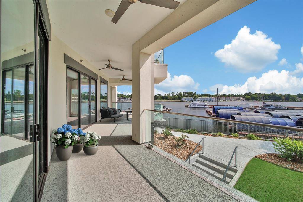 This waterfront property features a spacious covered terrace with ceiling fans, offering a serene view of a marina with boats. The space is perfect for outdoor relaxation and entertainment.
