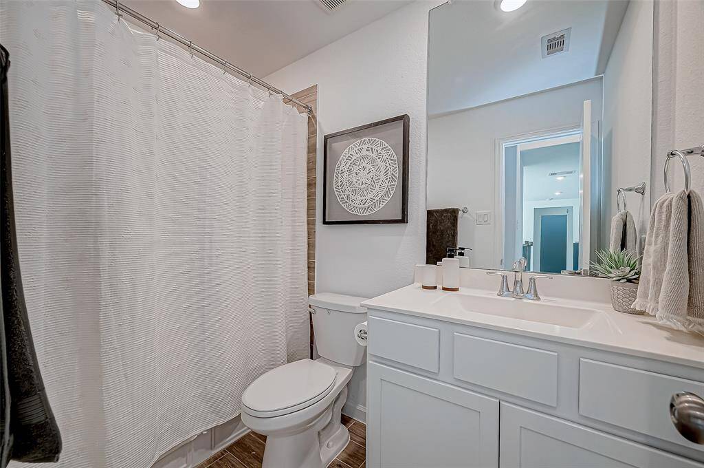 The secondary bathroom features a clean, modern design with a white vanity and sink, a large mirror, and a shower. It has stylish decor and ample lighting, creating a fresh and inviting atmosphere.